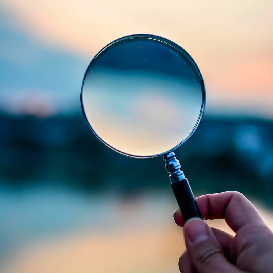 Main qui tient une loupe représentant d'expertise
