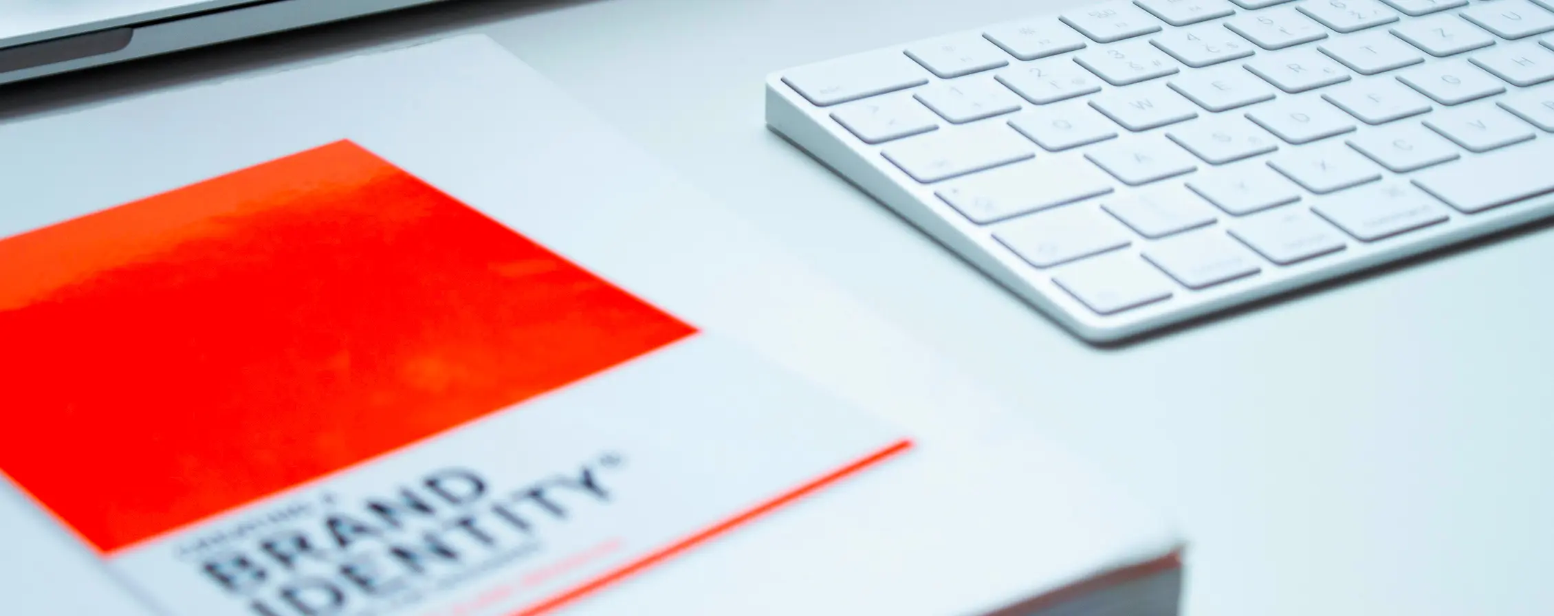 Cahier "brand identity" sur posé sur un bureau près d'un clavier d'ordinateur pour illustrer